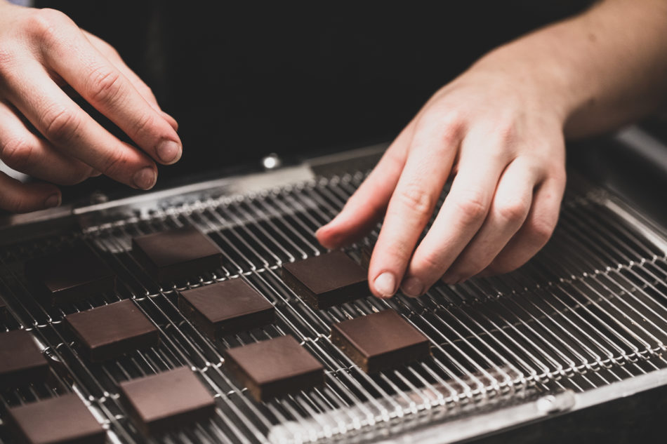 Ganaches chocolats posées sur grille, avec mains.